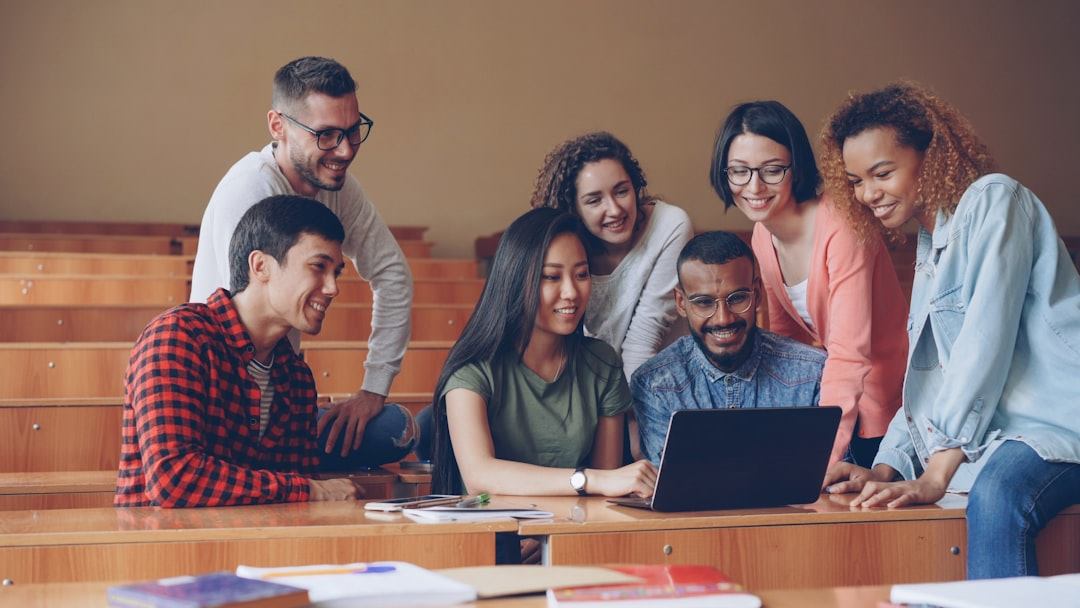 A group of people sitting together and using a laptop