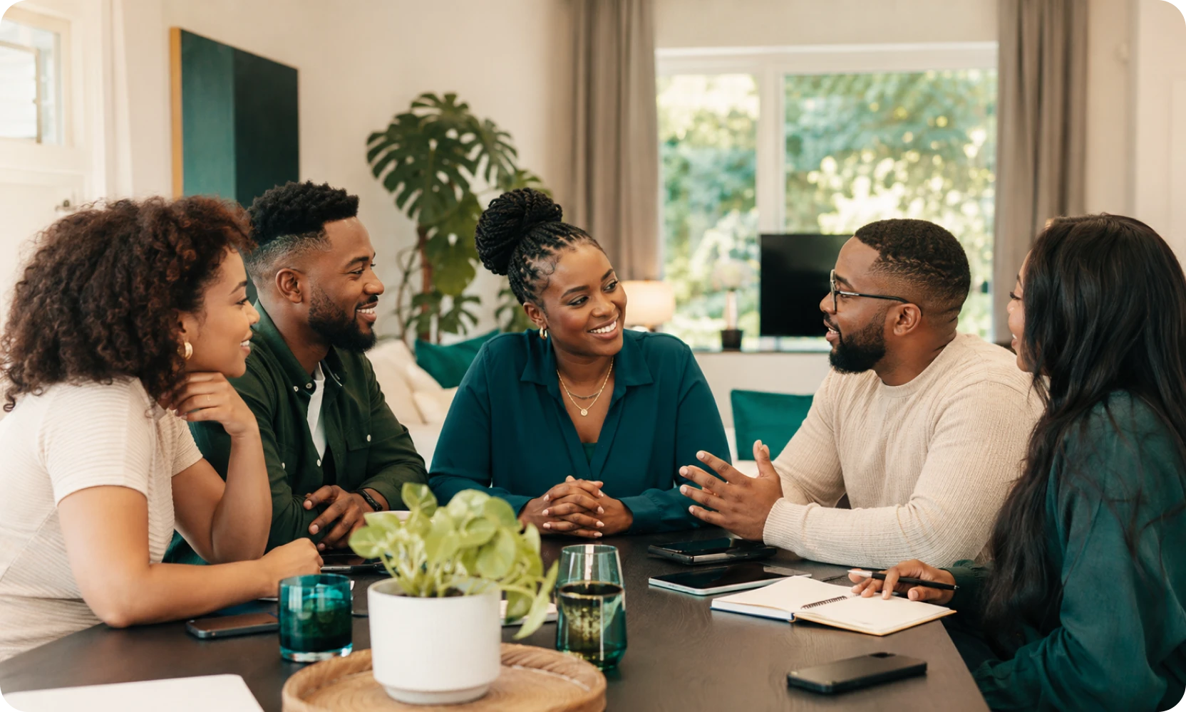 Five friends talking around a table during a savings group meeting